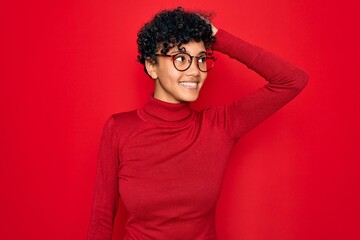 Fototapeta na wymiar Young beautiful african american afro woman wearing turtleneck sweater and glasses smiling confident touching hair with hand up gesture, posing attractive and fashionable