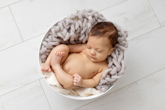 Newborn baby sleeping naked in a cocoon, top view