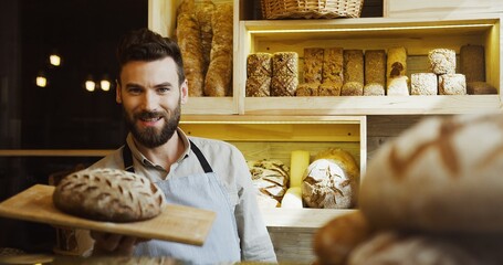 Portrait of handsome smiling baker working in bakery shop