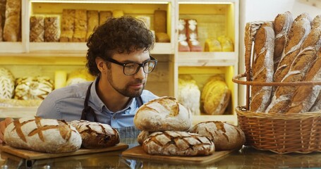 Obraz na płótnie Canvas Portrait of handsome smiling baker working in bakery shop