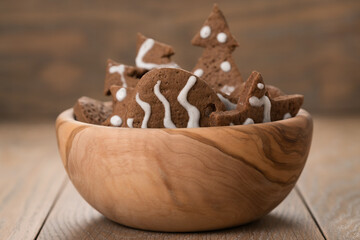 Gingerbread chrismas cookies in olive bowl on oak wood background with copy space
