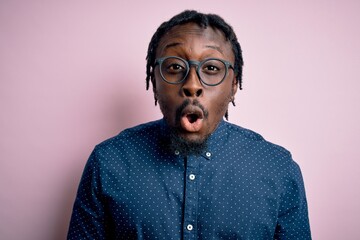 Young handsome african american man wearing casual shirt and glasses over pink background afraid and shocked with surprise expression, fear and excited face.