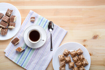 Cup of coffee on napkins on a wooden table with croissants and sweets.