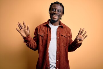Young handsome african american man wearing casual jacket standing over yellow background showing...