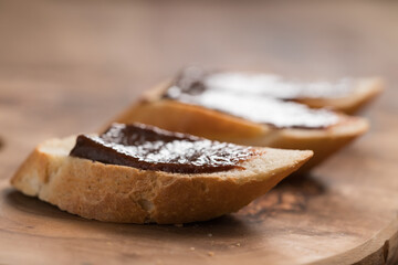 sweet breakfast baguette with chocolate hazelnut spread on wood board