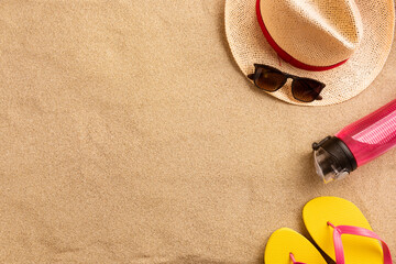 Fototapeta na wymiar Summer vacation composition. Flip flops, hat and other stuff on sand background