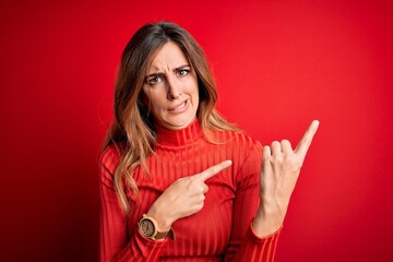 Young beautiful brunette woman wearing casual turtleneck sweater over red background Pointing aside...
