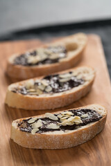 sweet breakfast ciabatta with chocolate hazelnut spread and almond flakes on wood board