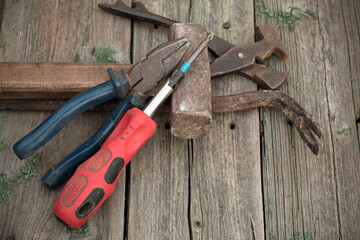 Top view of working tool hammer, nail puller, tire iron, pliers, screwdriver on a wooden background. Tool for men. Tool for carpentry work in production.