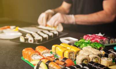 Cook hands making Japanese sushi roll. Japanese chef at work preparing delicious sushi roll with eel and avocado