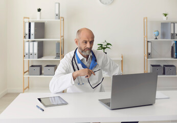 Senior doctor consulting patient online at clinic. Doctor online. Mature physician conducting video...