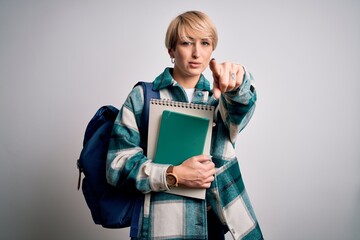 Young blonde student woman with short hair wearing backpack and holding university books pointing with finger to the camera and to you, hand sign, positive and confident gesture from the front