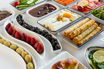 Traditional Turkish Breakfast Table with cheese,olives,fruits,patty,tomato and jam on the white surface.Buffet style