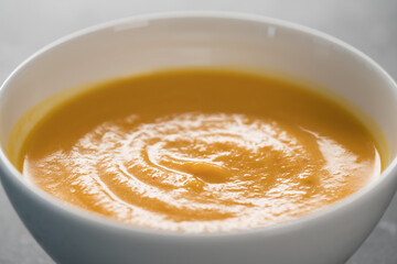 Pumpkin spicy soup puree in white bowl on closeup