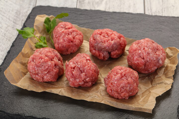 Raw meatball over wooden background