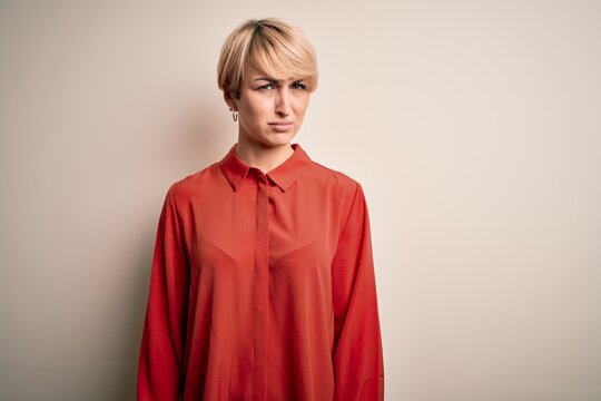 Young beautiful business blonde woman with short hair standing over isolated background skeptic and nervous, frowning upset because of problem. Negative person.