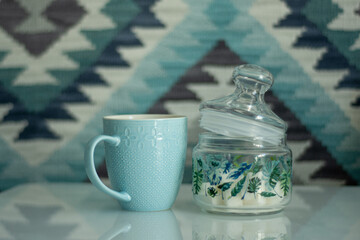 Obraz na płótnie Canvas A blue mug and sugar bowl on a white table. The background is bright blue in an ethnic style