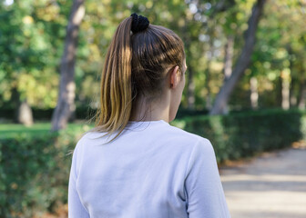 Back view of a blonde female runner in a white t-shirt in a park