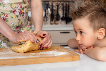 Obraz na płótnie Canvas Son helps his mom prepare cookie dough
