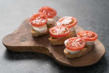 Bruschetta with tomatoes, mozzarella and pesto on olive wood board