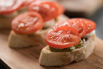 Bruschetta with tomatoes, mozzarella and pesto on olive wood board