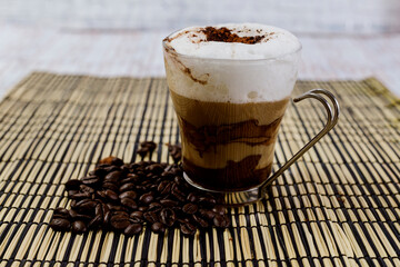 Cup of espresso coffee with chocolate and milk cream next to coffee bean