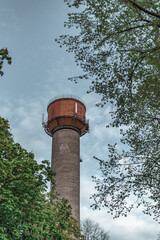 A brick tower in eastern europe between green leaves