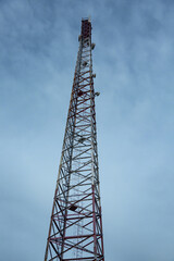 Cone-shaped metal mobile communications tower cell site against the sky at dusk. Vertical orientation. 