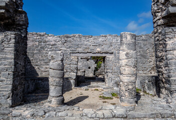 Naklejka premium Old stone entrance of a building in ruins situated in the ancient Mayan city of Tulum in Quintana Roo, Mexico.