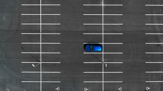 Top view on an empty parking lots with one blue car. Aerial view of car park.