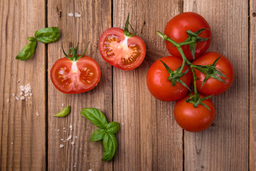 Fresh tomatoes with basil on wooden background. Copy space, top view.