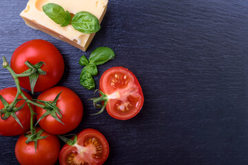  tomatoes,  cheese and basil  on black board. Italian food ingredients.