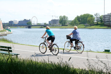 The motion blurred silhouettes of a women ridding a bicycles along a bicycle path along the Vistula river  in Cracow on a warm summer day. Poland.