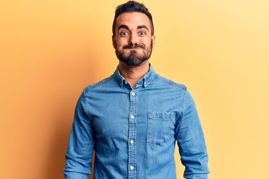 Young hispanic man wearing casual clothes puffing cheeks with funny face. mouth inflated with air, crazy expression.