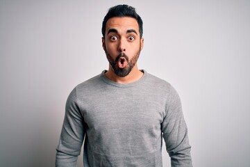 Obraz premium Young handsome man with beard wearing casual sweater standing over white background afraid and shocked with surprise expression, fear and excited face.