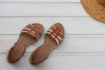 Women's sandals and hat on a white wooden background. Summer footwear