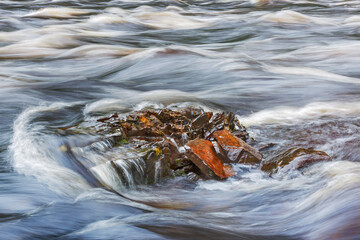 Stormy stream of the river washes stones, close-up, blurred background copy space