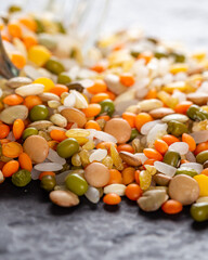 Colorful assorted lentils and whole grains seeds poured from a glass jar on the table