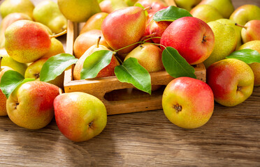 fresh pears with leaves in a box on a wooden table