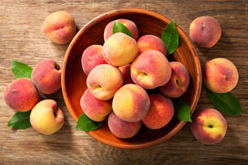 Naklejka na ściany i meble fresh ripe peaches with leaves in a bowl, top view