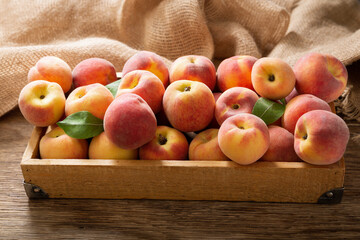 fresh ripe peaches with leaves in a wooden box