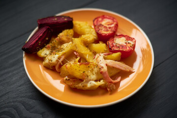 Baked potatoes with bacon, cheese and tomatoes in a plate.