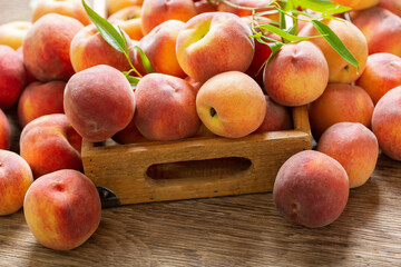 fresh ripe peaches with leaves in a wooden box