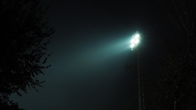 The stadium lights turned on at night. Floodlights at the stadium at night