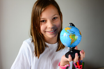 Adorable school girl studies earths geography on the small globe
