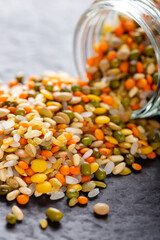 Colorful assorted lentils and whole grains seeds poured from a glass jar on the table