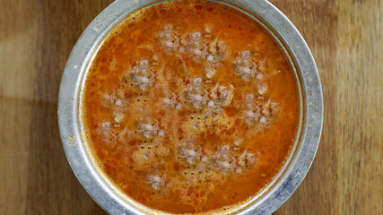 Beyran soup in a bowl / plate with spoons on the wooden table. Traditional hot soup of Gaziantep, Turkey. Closeup of a famous Turkish cuisine fresh food foams. Meat ingredients in regional breakfast.