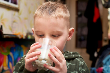 The boy is drinking milk from a glass.