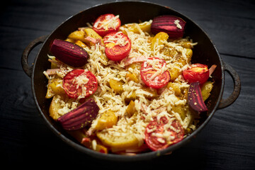 Baked potato with meat, tomatoes, beetroot in the oven. Sprinkled with cheese.