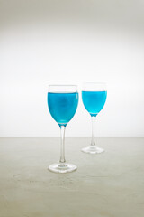 Two glasses of blue glitter drink on a light background. Sparkling blue wine.